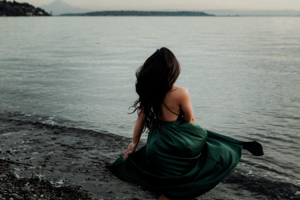 A woman dancing in front of the sea embodies the divine feminine archetype of the wild woman.